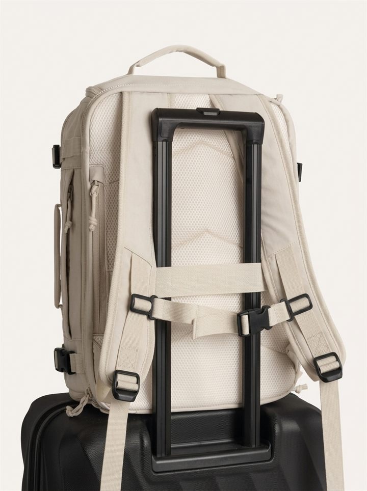 Backpack sliding onto a suitcase handle with the trolley strap